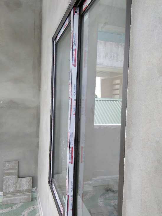 Cửa kính lùa khung nhôm đang lắp đặt trên tường bê tông trong ngôi nhà đang xây dựng